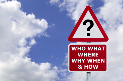 A triangular red and white road sign with a question mark in the center is mounted above a red rectangular sign that reads, "WHO WHAT WHERE WHY WHEN & HOW." The signs, reminiscent of an interview checklist, are set against a backdrop of a blue sky with scattered clouds.