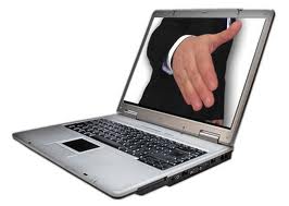 An open laptop displays an image of a person in a black suit extending their hand, as if offering a handshake through the screen. The laptop, with its silver body and black keyboard, captures the essence of Virtual Career Fairs perfectly.