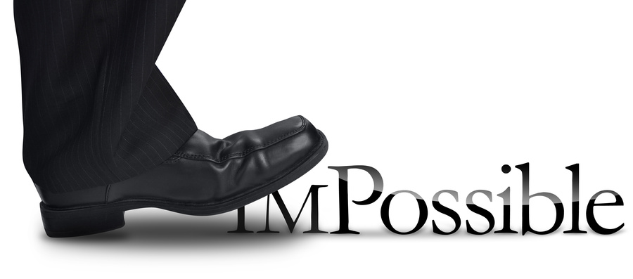 A black shoe, worn by a person in black pants, is stepping on the word "Impossible," causing the first two letters "IM" to bend and fall, transforming the word into "Possible." This powerful image reflects effective managing. The background is white.