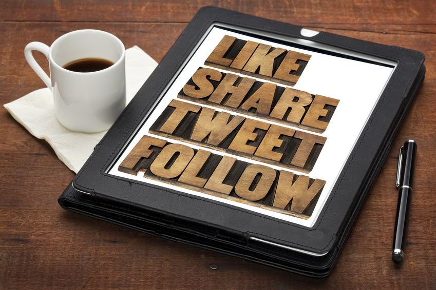 A tablet on a wooden table displays the words "LIKE SHARE TWEET FOLLOW" in wooden block letters. A cup of black coffee on a napkin, a black pen, and a leather case are also on the table, setting the scene for an efficient recruiting process.