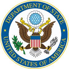 Seal of the U.S. Department of State, featuring an American bald eagle holding an olive branch and arrows. The eagle's chest bears a red, white, and blue shield. Above its head, a blue circle with white stars is surrounded by clouds. The outer border reads "Department of State" and "United States of America.