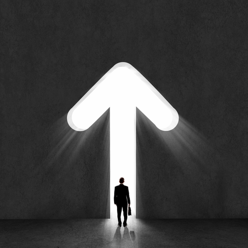 A silhouette of a man holding a briefcase stands before a large illuminated arrow pointing upward on a dark background, suggesting progress, leadership, and direction.