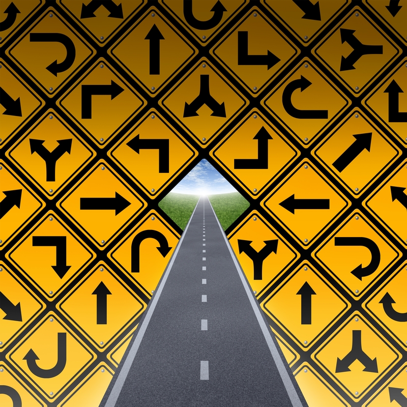 A straight road leads to a bright sky in the distance, surrounded by a wall of yellow road signs depicting various directional arrows, including turns and curves. The signs create a pattern, forming a triangular opening above the road, symbolizing the journey of one's career.