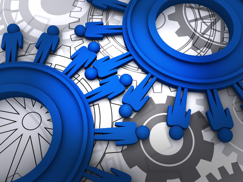 Illustration of blue human figures forming a network, connected like cogs in machinery with interlocking gears in the background. The image symbolizes HR innovation, teamwork, collaboration, and interconnected systems.