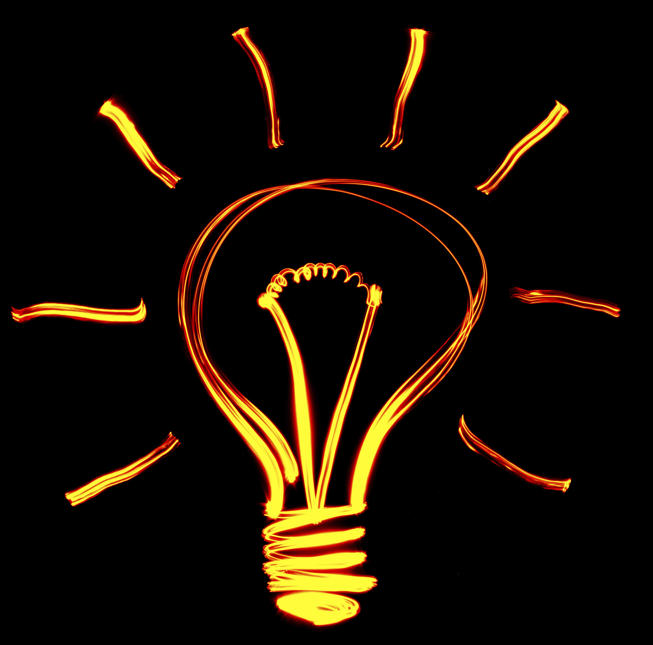 A glowing outline of a light bulb is drawn against a black background with bright orange light. Curved lines radiate outward from the top half of the bulb, symbolizing illumination and ideas—just like recruiters shining a light on hidden potential.