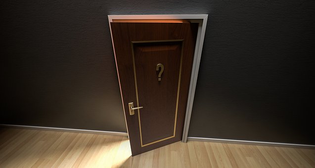 A slightly open wooden door with a question mark symbol on it, set against a dark wall, allowing a warm light to peek through the gap. The scene evokes a sense of career-related mystery and curiosity.
