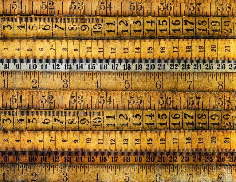 A collection of vintage, weathered measuring tapes with numbers and calibration marks, arranged horizontally in overlapping layers. The resume-length tapes show signs of age, with faded and darkened areas, giving them an antiquated look.