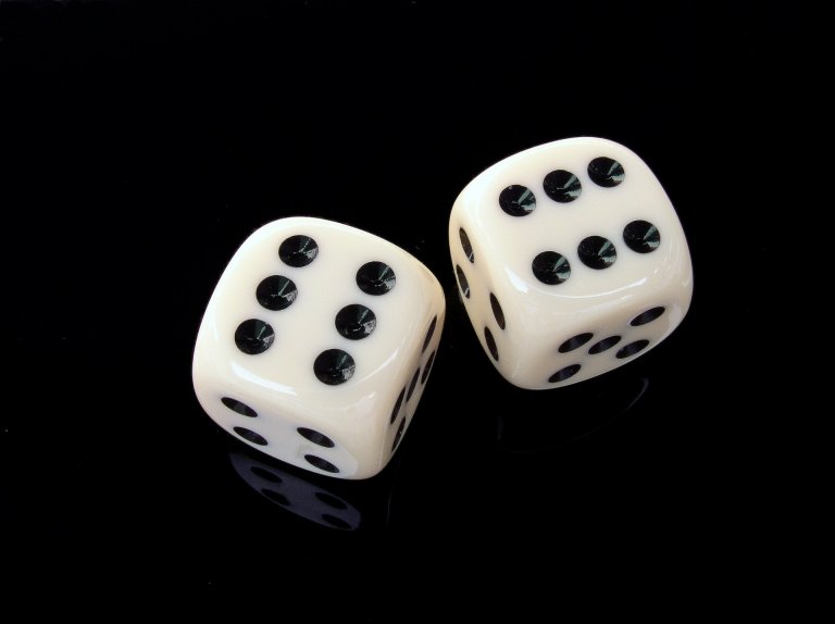 Two white six-sided dice with black dots showing the numbers six and two rest on a glossy black surface, as if waiting for influencers to roll them in a high-stakes game.
