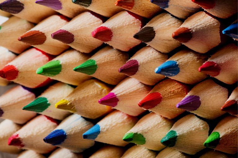 A close-up image of a tightly packed bundle of colored writing pencils. The pencils are arranged with their tips facing outward, displaying a variety of vivid colors including red, green, blue, yellow, purple, and more, forming an eye-catching pattern.