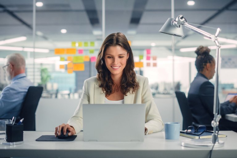 A woman happily working in the office with her colleagues