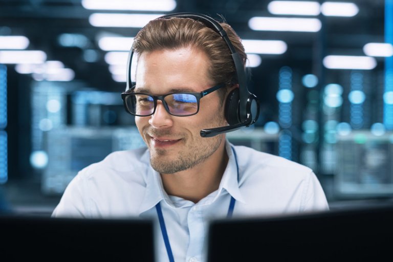 A staff with headphones talking to clients while facing his desktop