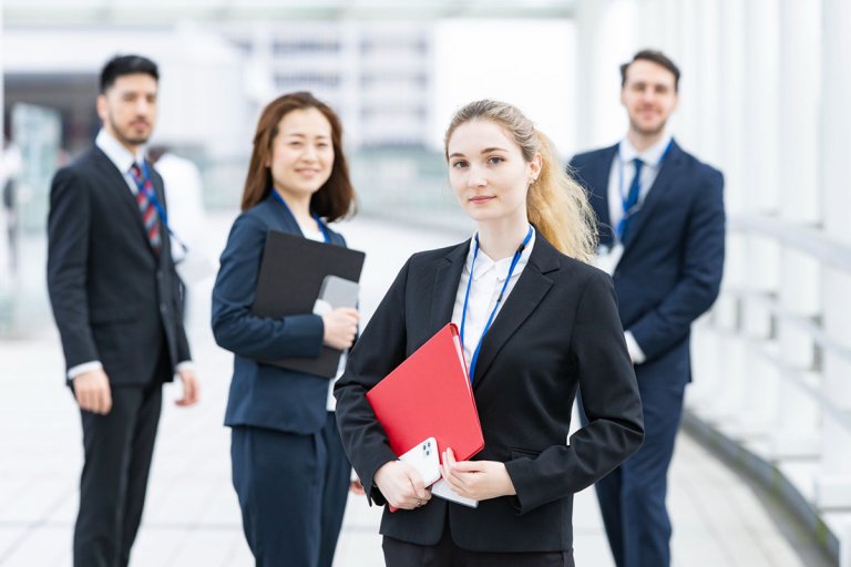 Four employees standing proudly outside the company building