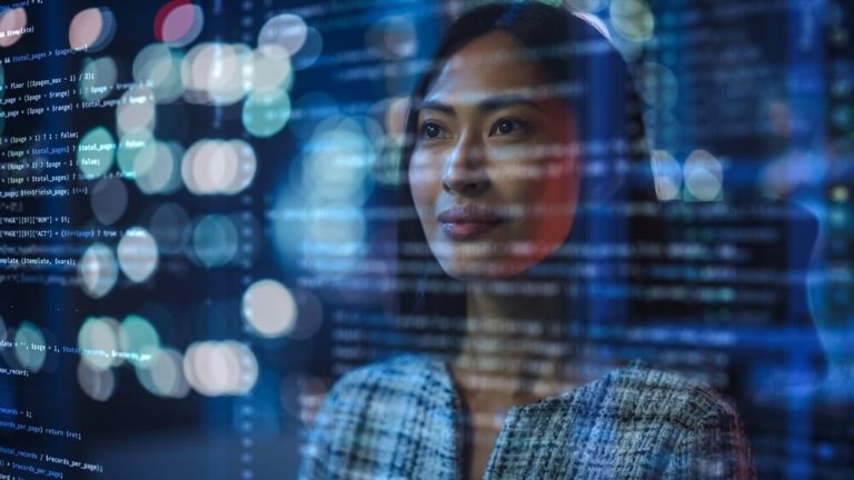 A woman stands, looking thoughtfully at lines of computer code and government data superimposed over her image. Out-of-focus city lights create a bokeh effect in the background, adding a sense of depth and modernity.