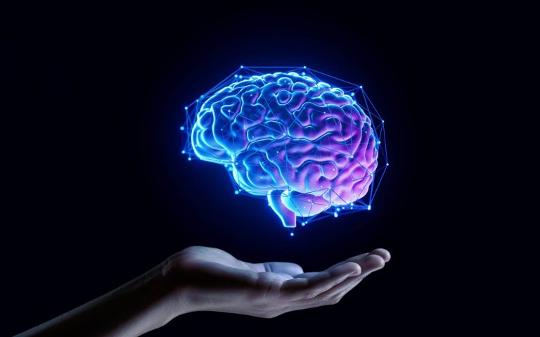 A glowing digital illustration of a human brain hovers above an open hand against a black background, with blue and purple tones and connected nodes forming a network—symbolizing intelligent workforces of the future.